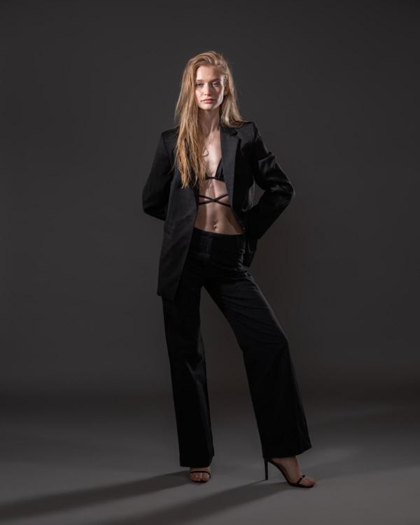Caucasian female model in baggy black suit and bralette photographed by Marty Gottlieb